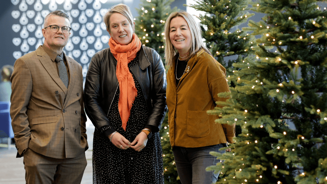 a man and two women beside a christmas tree
