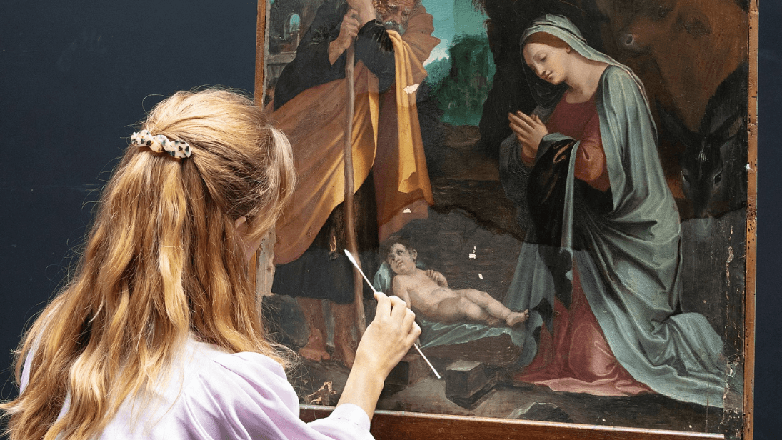Conservation Fellow at the National Gallery seated restoring Baldassare Tommaso Peruzzi's The Nativity. 