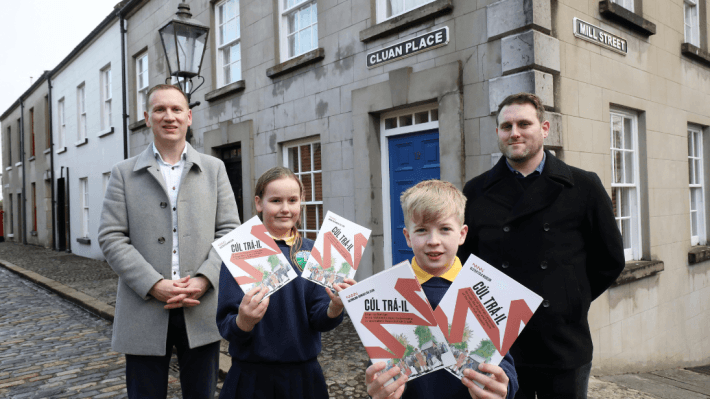 Adults and children holding booklets pictured at Cluan Place at Ulster Folk Museum to launch Irish language trail Cúl Trá-il