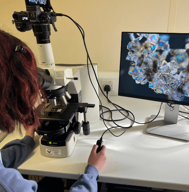 Girl using a microscope and seeing the results of a sponge spicule on a screen