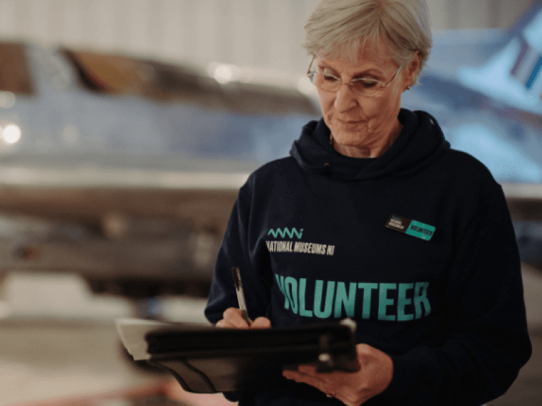 A female volunteer at the transport museum using a clip board to write